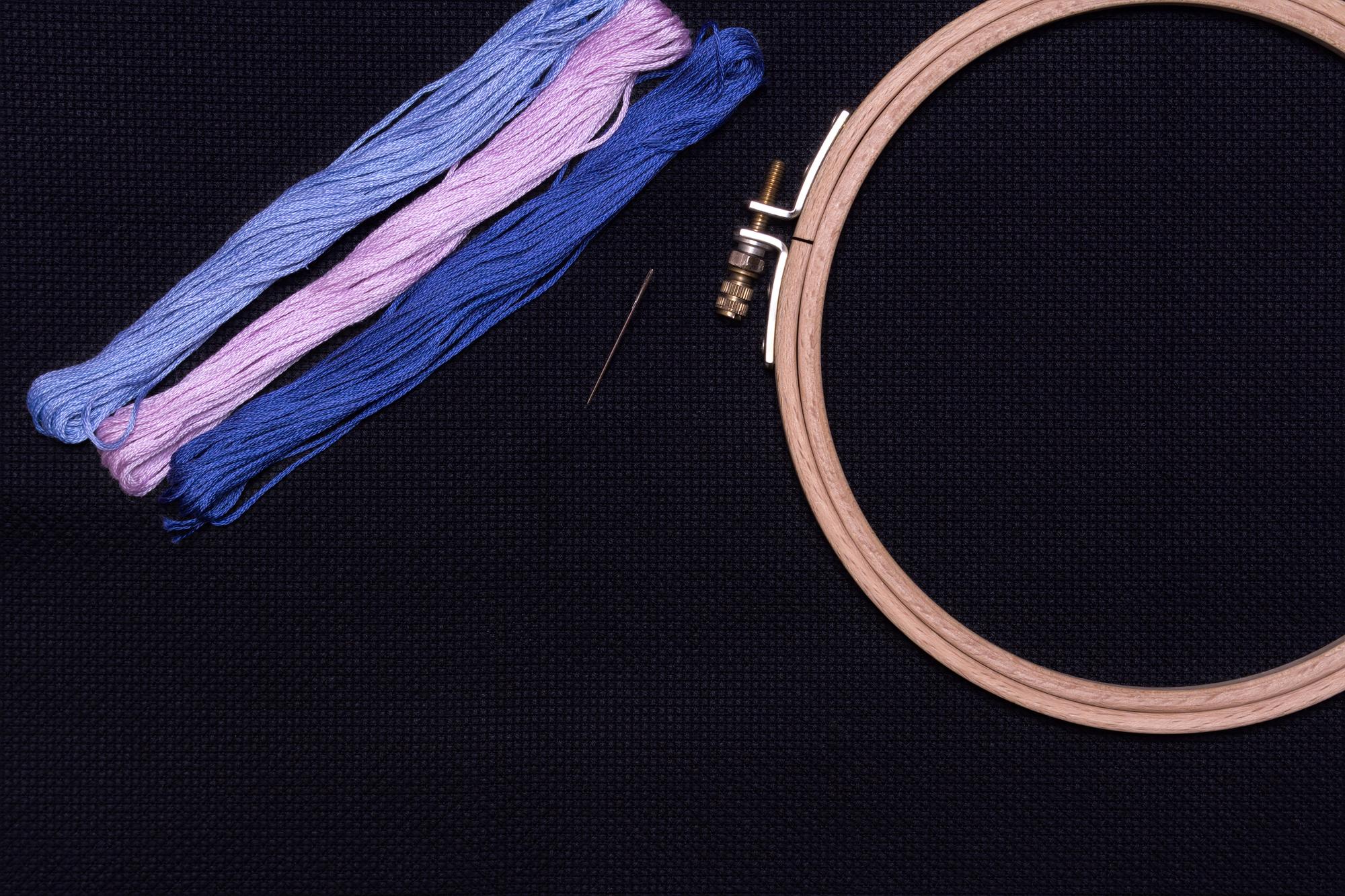 close-up of neon-thread embroidery hoop on black fabric